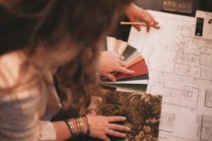 Designer consulting blueprints with fabric and color samples for interior project.